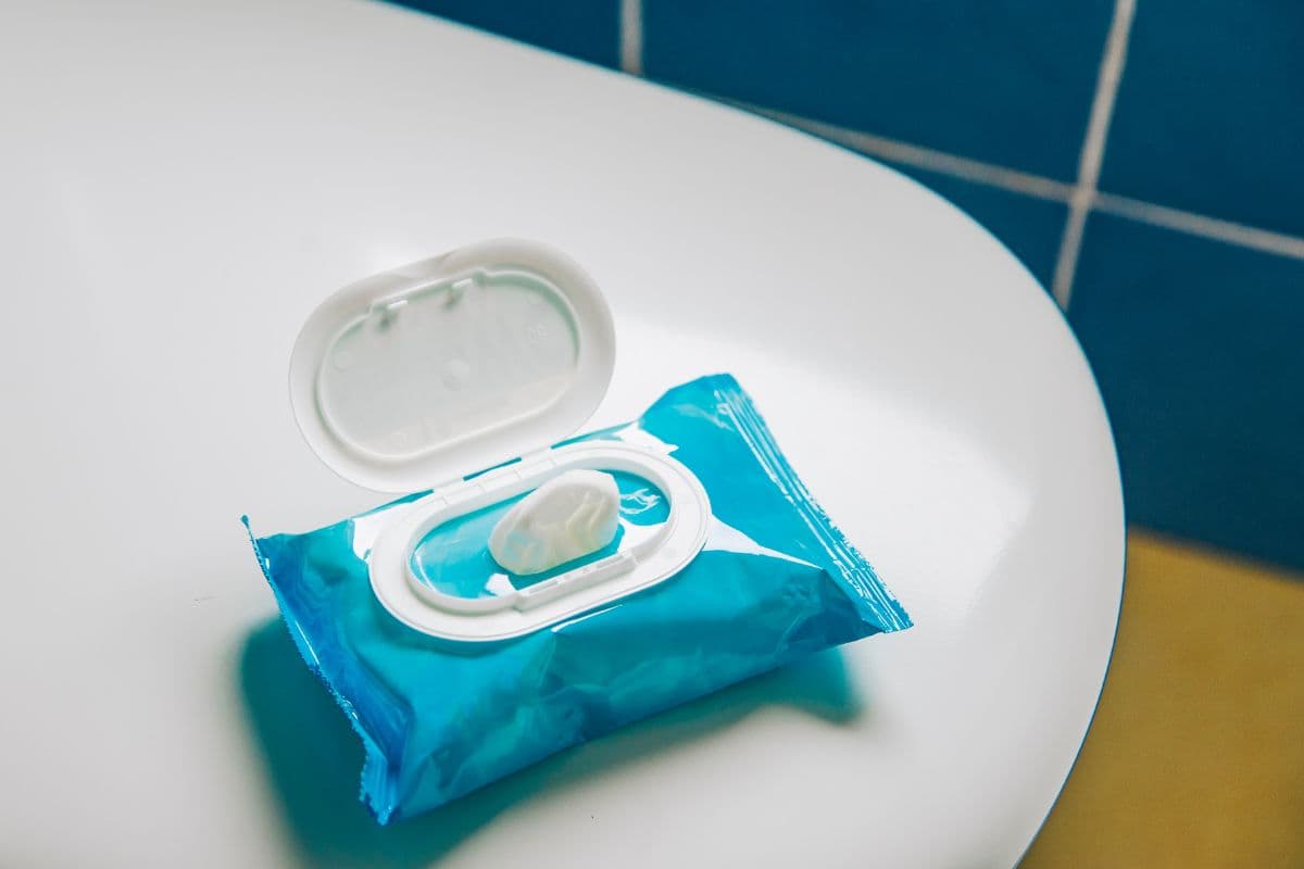 Package of flushable wipes next to a roll of toilet paper on a bathroom counter, illustrating the comparison consumers face when choosing what to flush