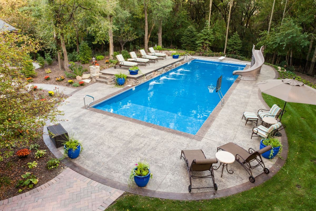 Residential in-ground swimming pool in a backyard with green lawn, illustrating pool and septic system coexistence on a private property.